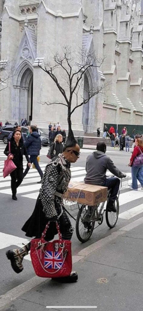 A woman carrying a Union Jack bag beside a bicycle